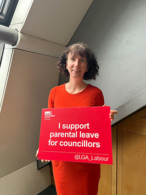 Anneliese Dodds MP holding sign supporting parental leave for councillors