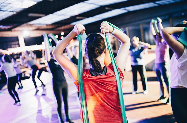 Women standing in a circle at a fitness class and using resistance bands
