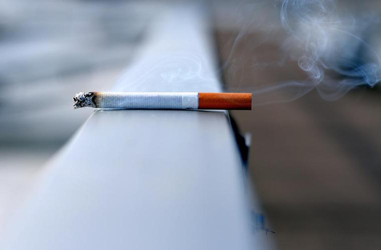 A cigarette burning left on top of a window sill