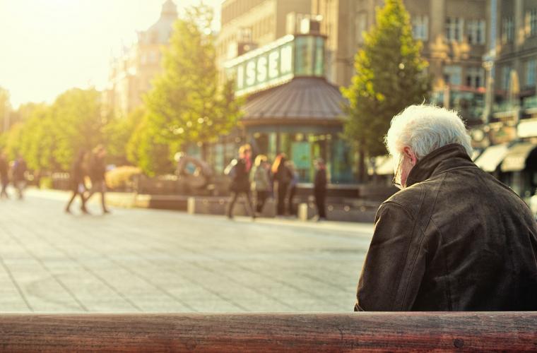 elderly man sitting alone on a bench in the town centre