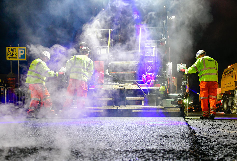 Men in high visibility jackets working on surfacing a road at night