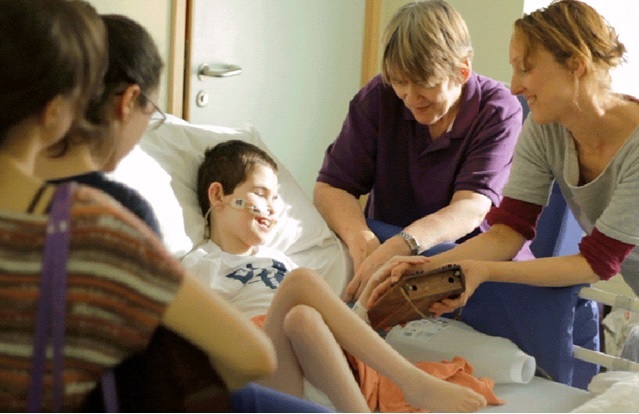 Carers helping a disabled person play an instrument