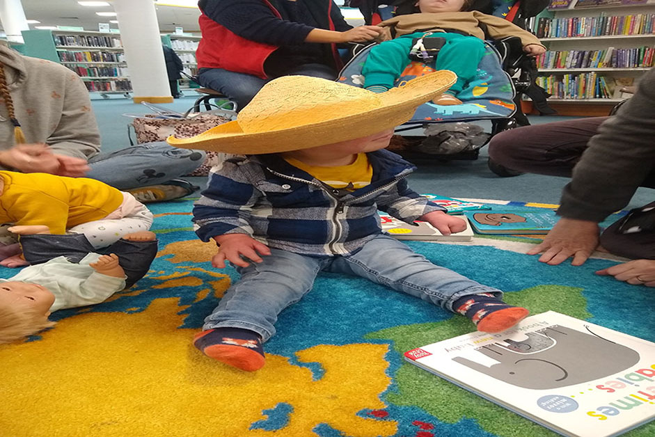 Child sitting on the floor wearing an over-sized Mexican styled hat 