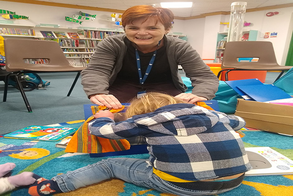 Dorset library social worker helping a special needs child sitting on the ground