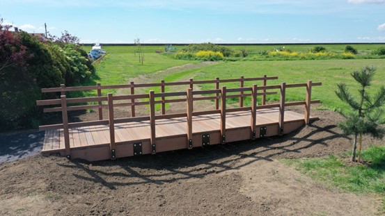 A wooden footbridge with green fields in the background