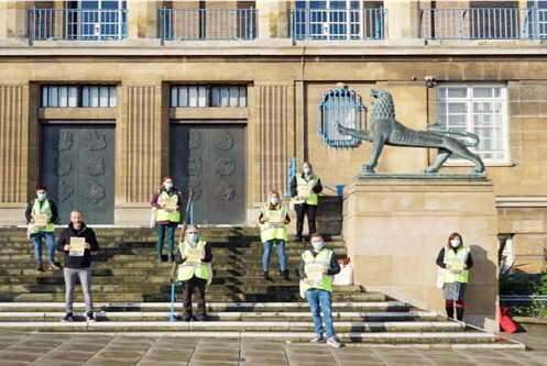 A photograph of Norwich council staff wearing masks outside the council building