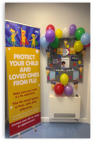 Flu Superhero big banner on the GP wall and colourful balloons near the banner