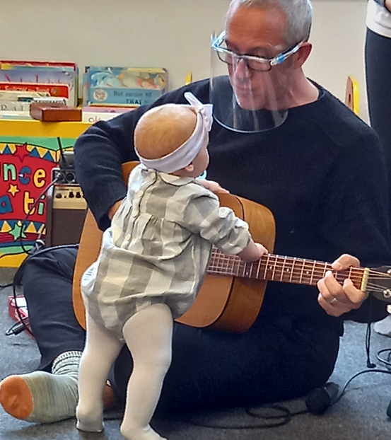 A person playing a guitar for a baby