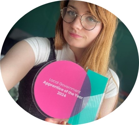 Sara holding an pink and green award for apprentice of the year.
