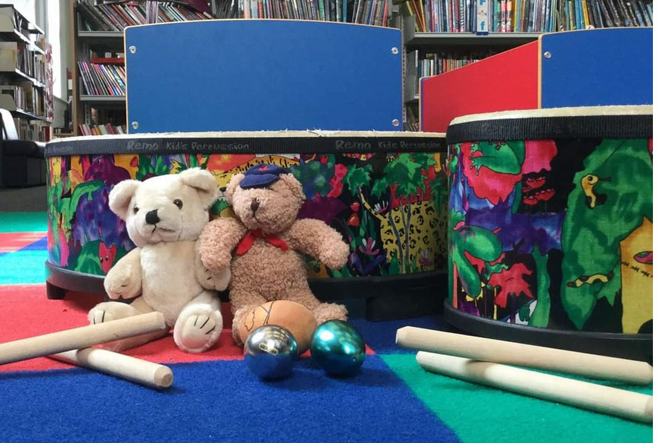 Two teddy bears and musical instruments in a library