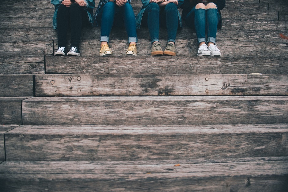 young people together sitting on a step, shot of lower legs and trainers