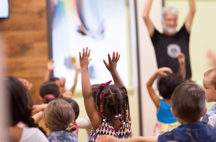 A mixed group of  children copying the dance movement of a teacher