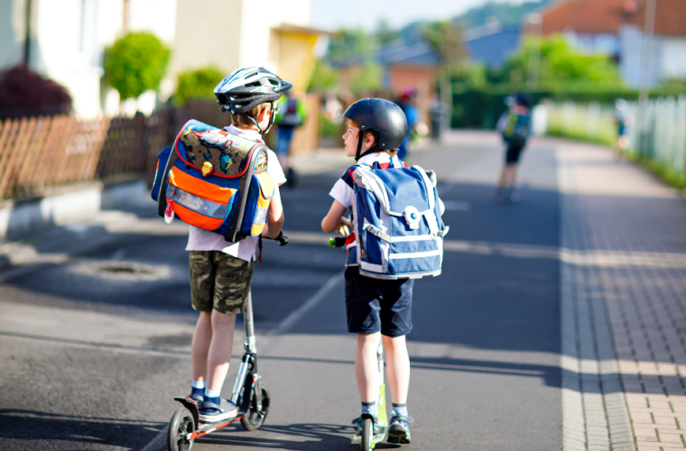 Two boys riding to school on scooters