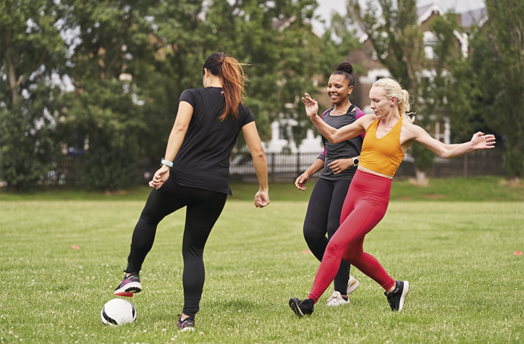 Three women playing football in a park
