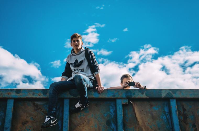 Photo of teenagers sitting on rubbish container