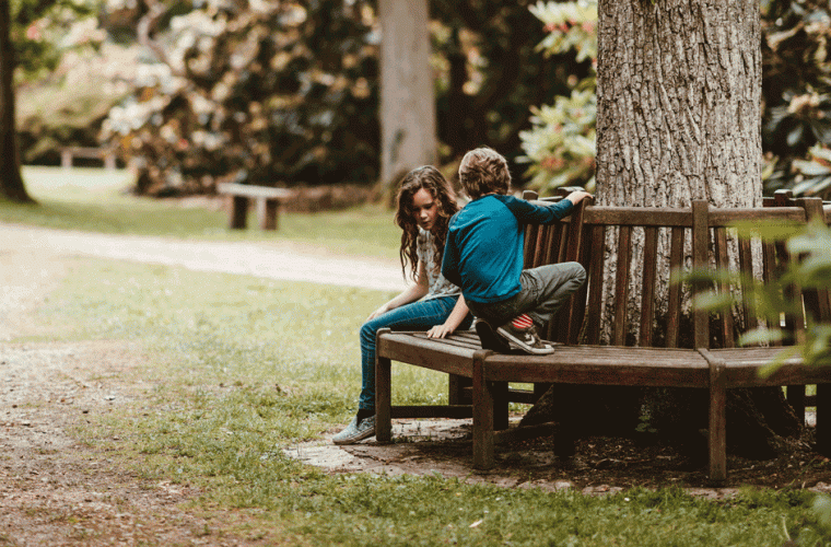 photo of boy and girl on a bench in a park 