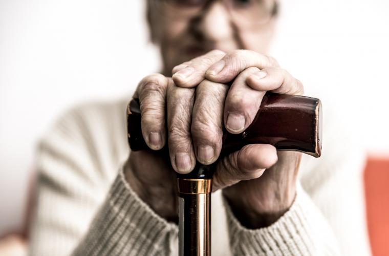 Close up of the hands of an elderly man with a cane