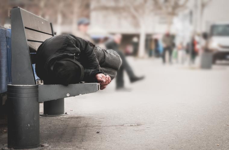 homeless person sleeping on a bench