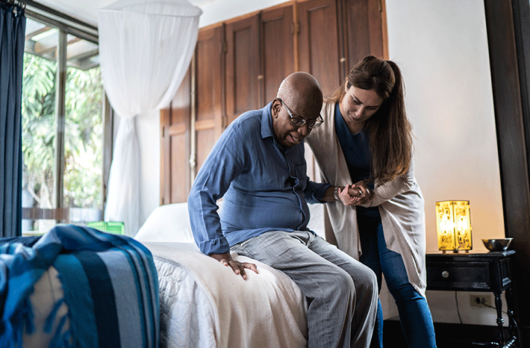 A young carer woman holding an elderly man's hand to help him to stand