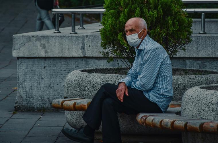 Person sitting down outside with mask on