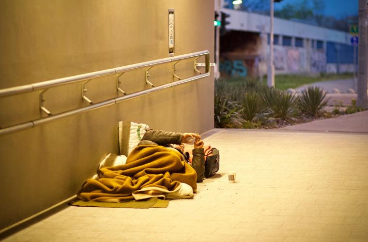 Man sleeping in a sleeping bag on the floor of an underpass