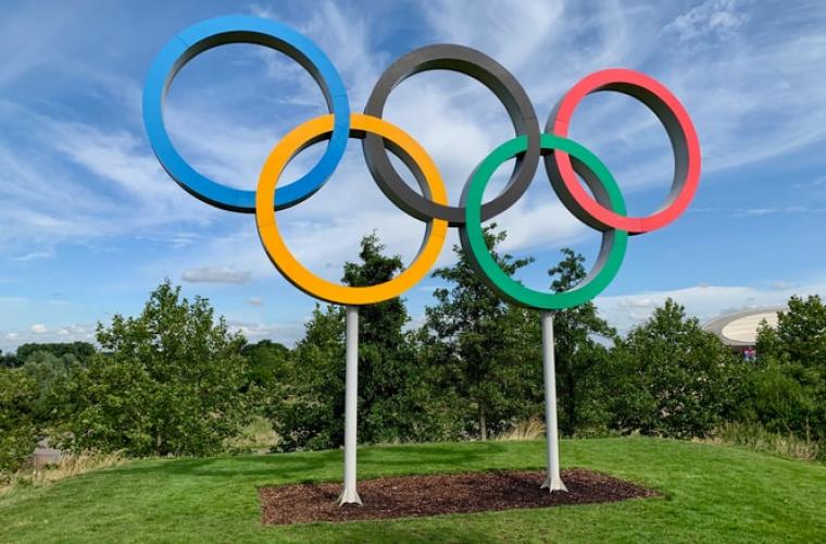 Olympic rings statue standing over some grass