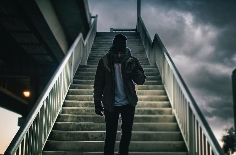 man walking down stairs with his hood up looking down