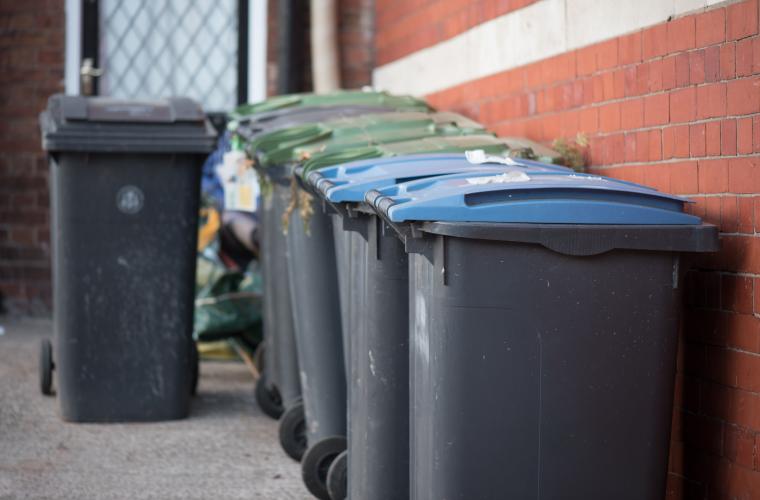 photo of row of bins by a red brick wall