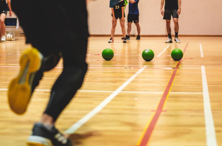 Image of a team of people playing dodgeball inside a sports hall