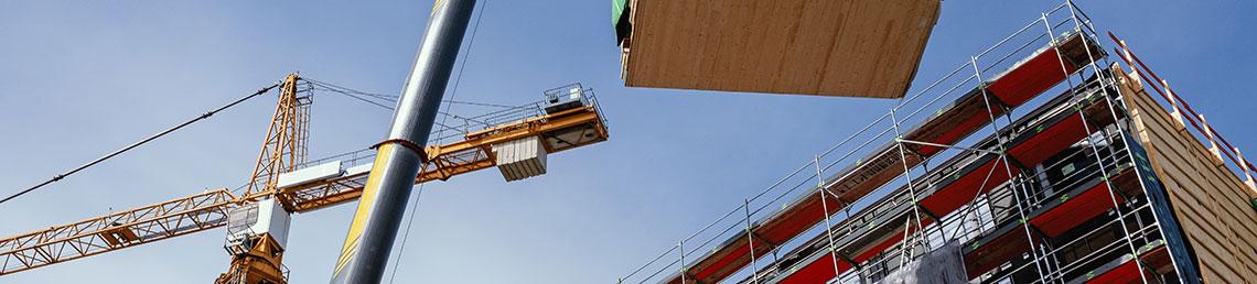 Crane lifting a prefabricated wooden building module to its position on construction site