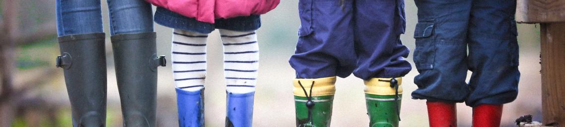 Row of children's legs in wellington boots
