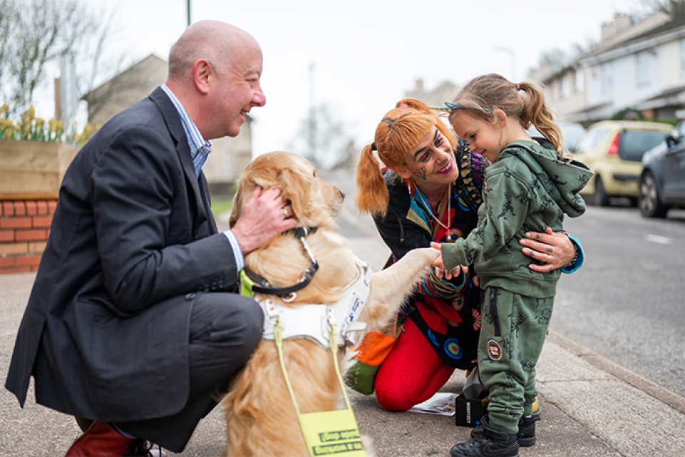 Councillor Steve with his guide dog greeting a young girl and her mum