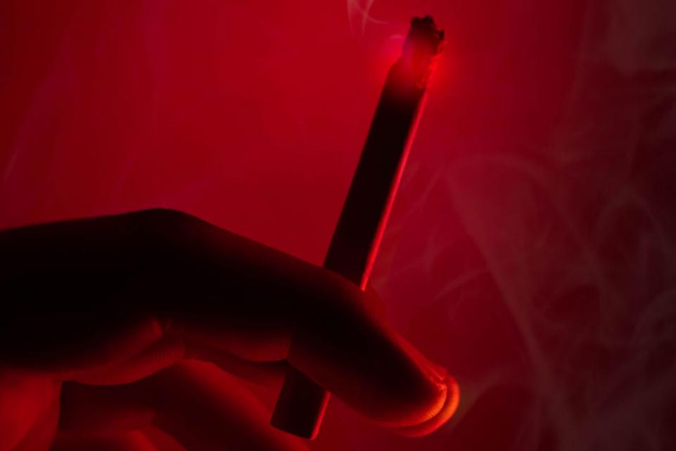 Hand holding a cigarette under a red light