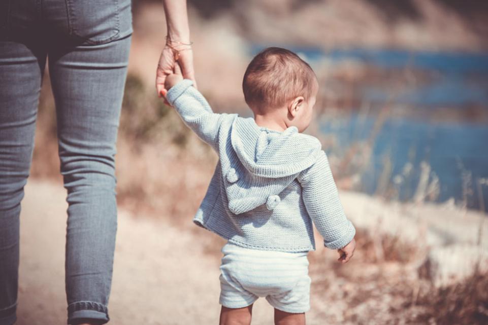 Toddler holding hands with woman