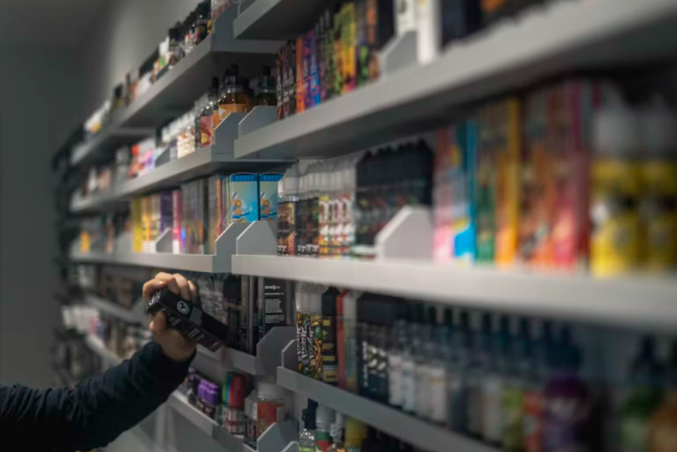 Person reaching for a vape from an aisle of colourful products